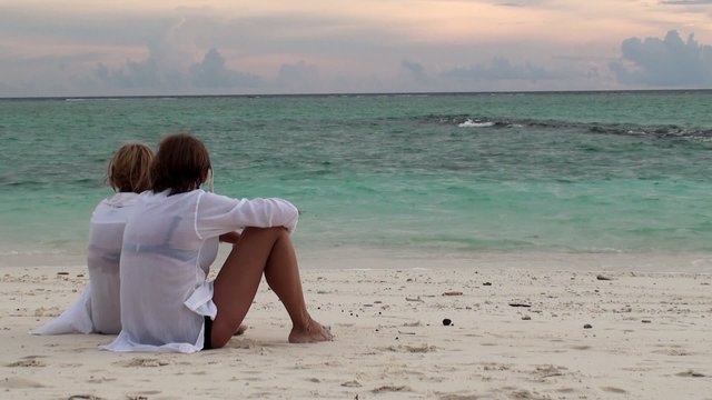 Two girls at the beach watching for the gray heron. Maldives.