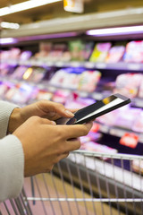 Woman using mobile phone while shopping in supermarket
