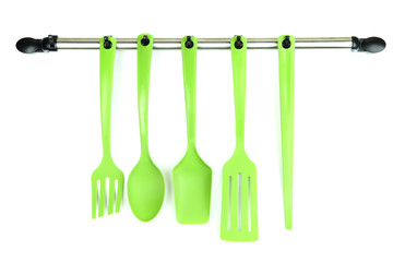 Plastic kitchen utensils on silver hooks isolated on white