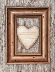 Wooden heart in frame on the old wood