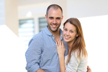 Cheerful couple standing in front of home