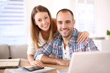 Young cheerful couple calculating savings for home investment