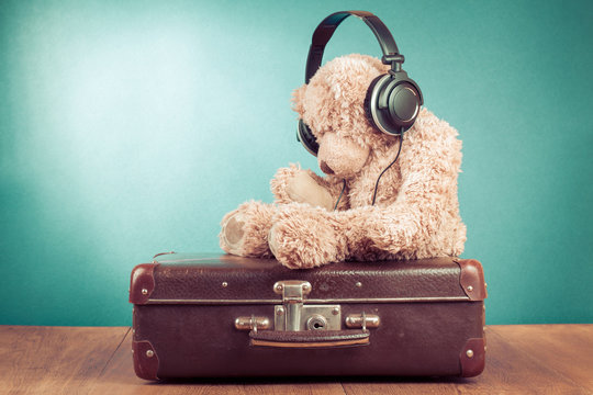 Retro Teddy Bear with headphones on old suitcase