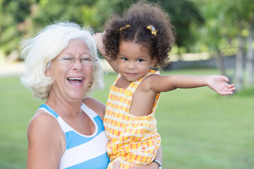 Latin girl and her caucasian grandmother hugging in a park - 57587887
