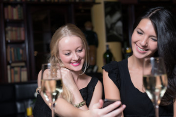 Two women on a night out using mobile phones
