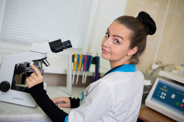 Portrait of a young woman doctor in clinic lab with microscope