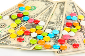 Colorful candies on dollar banknotes isolated on white