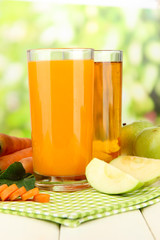 Glasses of juice, apples and carrots