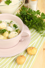 Tender young potatoes with sour cream and herbs in pan