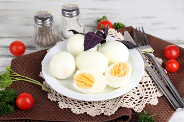 Boiled eggs on plate on napkin on wooden table