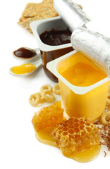 Tasty desserts in open plastic cups and honey combs, isolated
