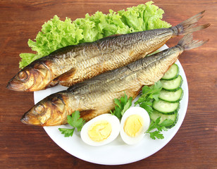 Smoked fish on plate on wooden table