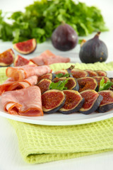 Tasty figs with ham on white wooden table