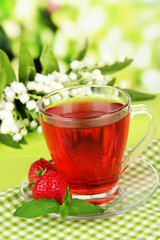 Delicious strawberry tea on table on bright background