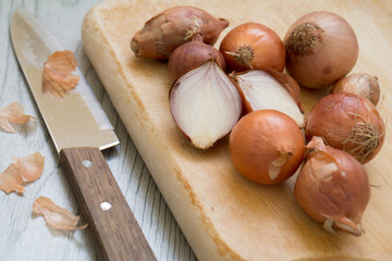 Shallots on wooden cutting board with knife