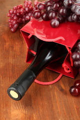 Gift box with wine on wooden table close-up