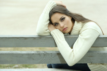 Young lonely woman on bench in park