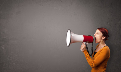 Girl shouting into megaphone on copy space background