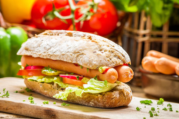 Closeup of hot dog with two sausages and fresh vegetables