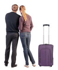 Back view of young couple traveling with suitcas .