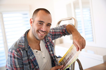 Cheerful guy in new apartment looking for paint colors