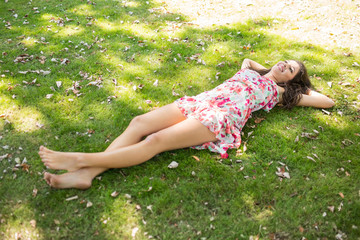 Naklejka na ściany i meble Stylish happy brunette lying on the grass
