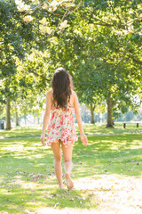 Naklejka premium Rear view of stylish brunette walking on grass
