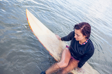 Beautiful woman sitting on surfboard in water