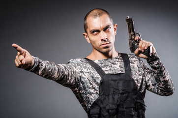 Soldier with guns against dark background
