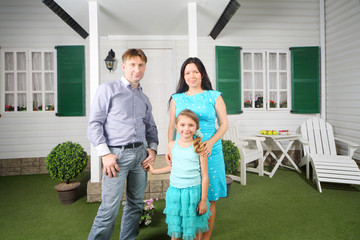 Fototapeta premium Smiling father, mother and daughter stand near porch