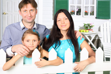 Smiling father, mother and little daughter stand