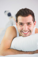 Cheerful handsome man lying in bed looking at camera