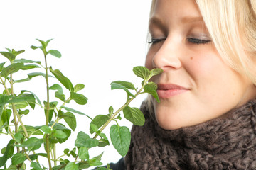 Blonde Frau riecht an Pfefferminzpflanze