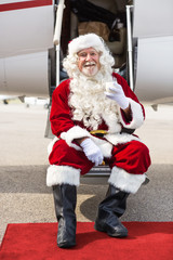 Santa Holding Milk Glass While Sitting On Private Jet's Ladder