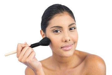 Pleased nude brunette using powder brush