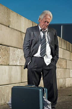 Depressed senior business man with suitcase without a job and ho