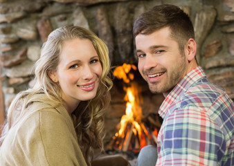 Smiling young couple in front of lit fireplace