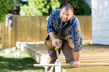 Manual Worker Sawing Wood At Construction Site