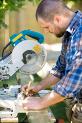 Carpenter Marking On Wood With Pencil At Table Saw