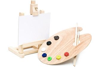 Wooden easel with clean paper and wooden artists palette loaded