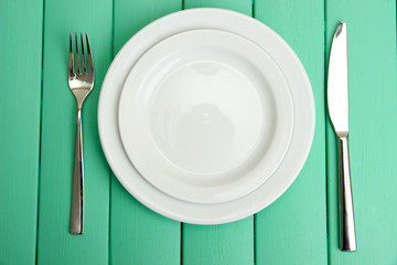 Plate and cutlery on wooden table close-up