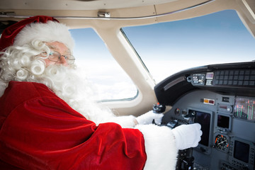 Santa Holding Control Wheel In Cockpit Of Private Jet