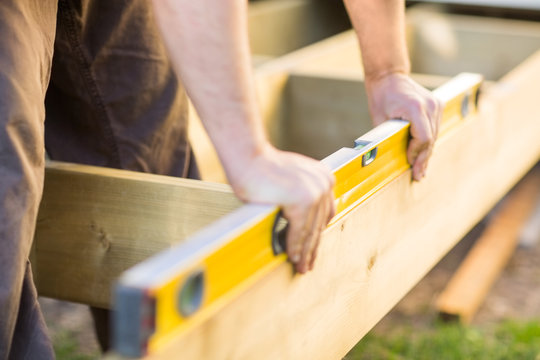 Carpenter's Hands Checking Level Of Wood At Site