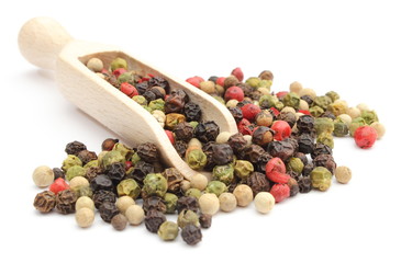 Colored pepper on a wooden spoon isolated on white background