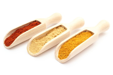 Three spices - curry, ginger and paprika - on wooden spoons