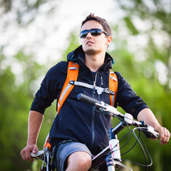Naklejka premium Handsome young man biking in the countryside