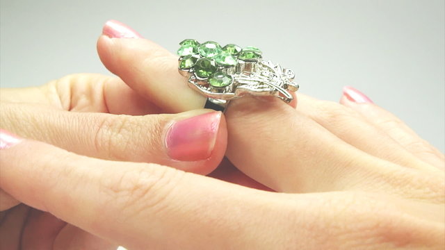 jewelery ring with green emerald crystals putting on the finger