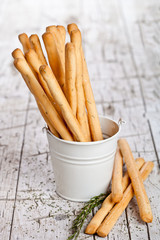 white bucket with bread sticks grissini and rosemary