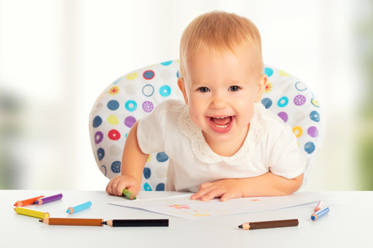 happy baby child draws with colored pencils crayons