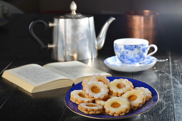 Delicious jam cookies with cup of English tea and book
